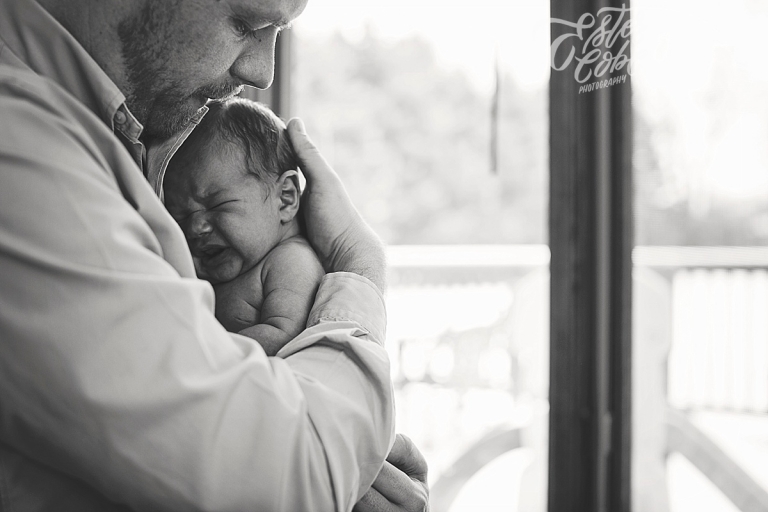 Father holding infant Newborn in Home Photography